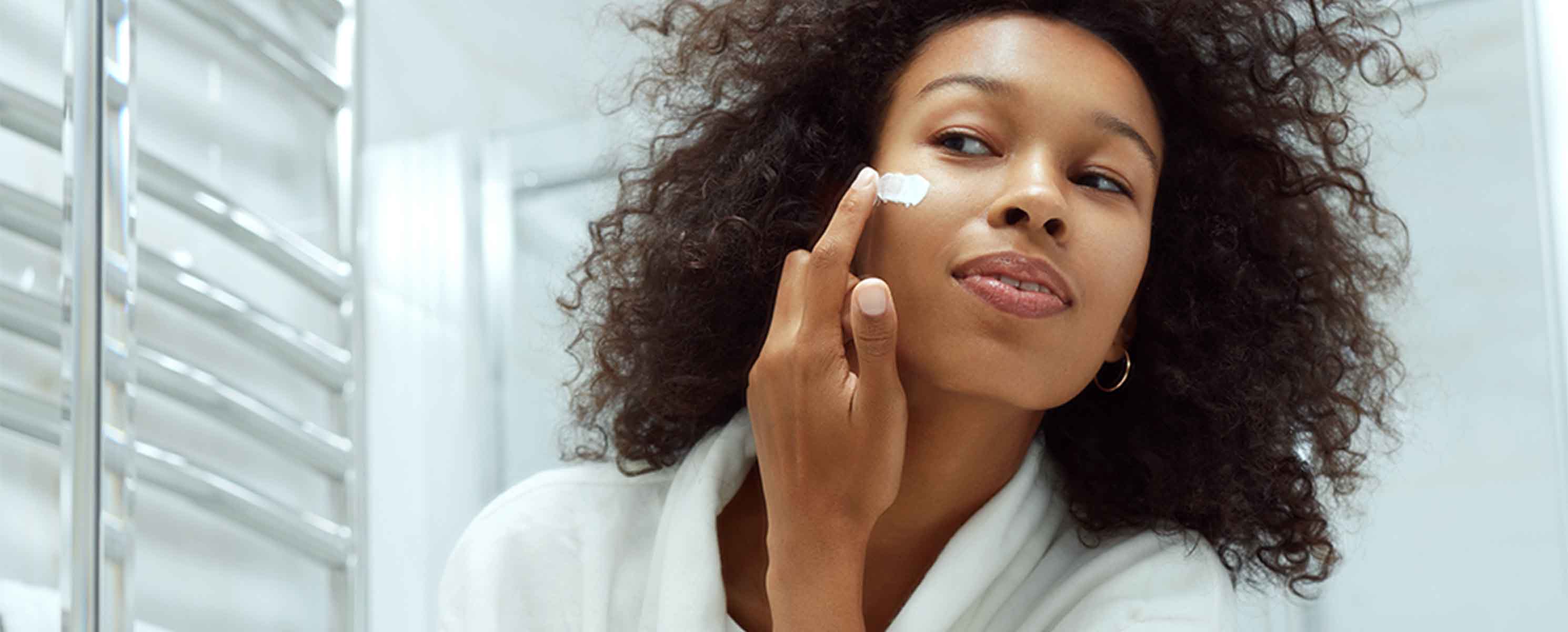 Young black woman applying sunscreen