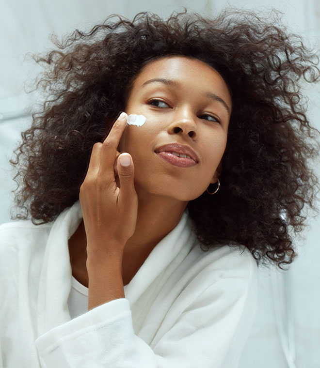 Young black woman applying sunscreen