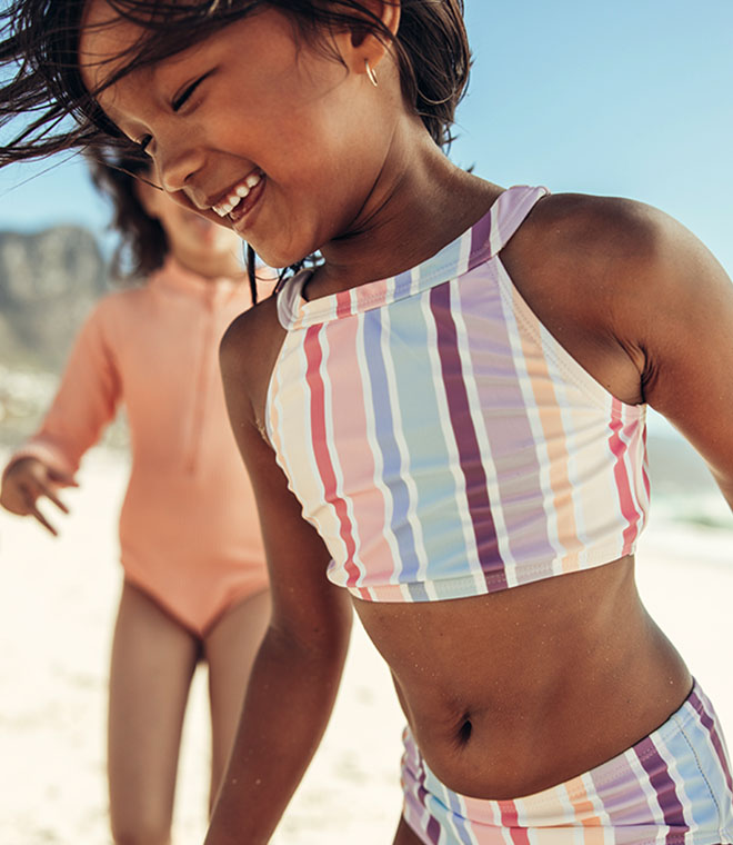 Little girl running around in a bathing suit 