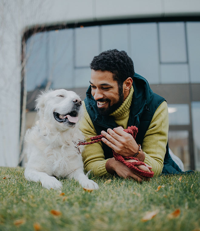 Happy man and dog laying in the grass