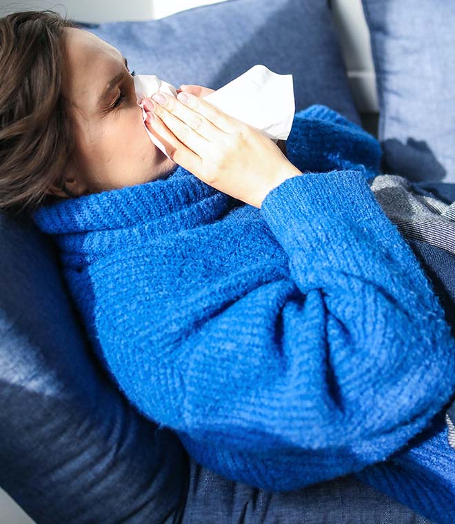 Woman in a blue robe blowing her nose