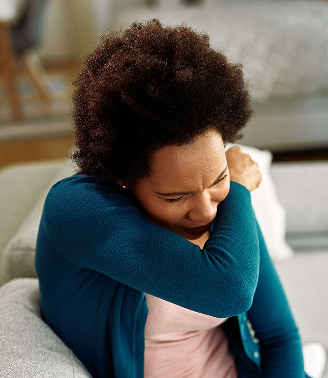 Black woman coughing into her elbow