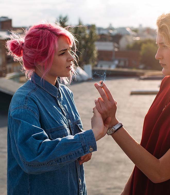 Young woman with pink hair pushing away a cigarette