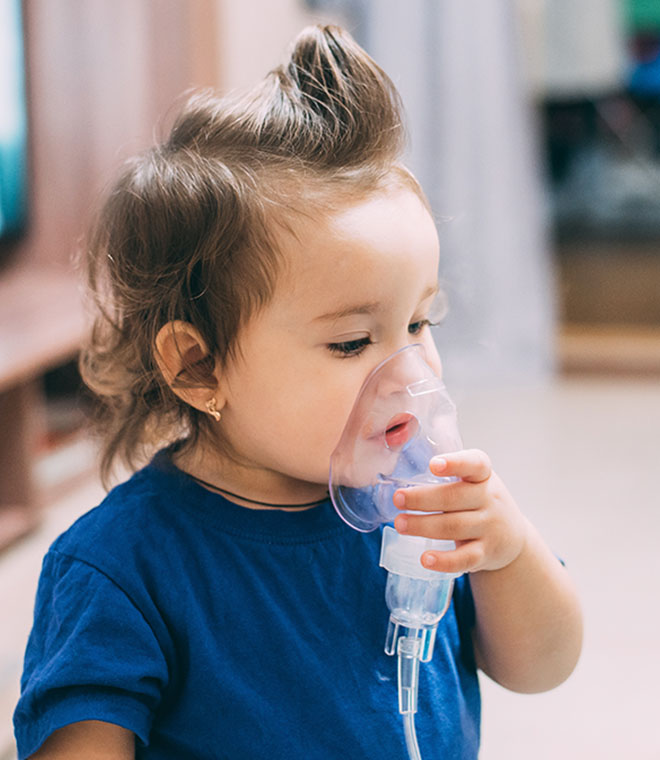 Toddler holding breathing mask to their face