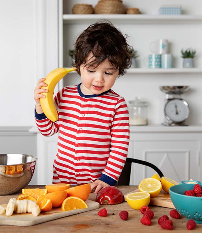 Toddler playing with fruit at a table