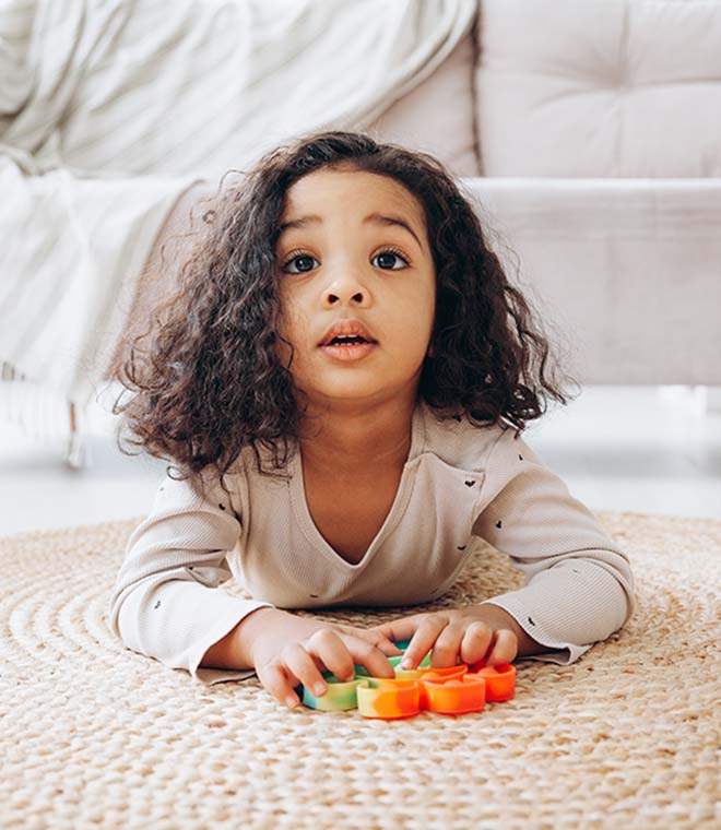 Young black girl playing on rug