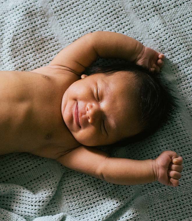 Baby in diaper lying on a bed