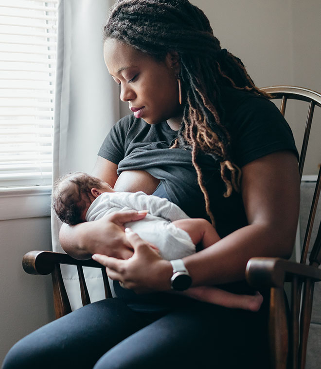 Black woman breastfeeding child at home