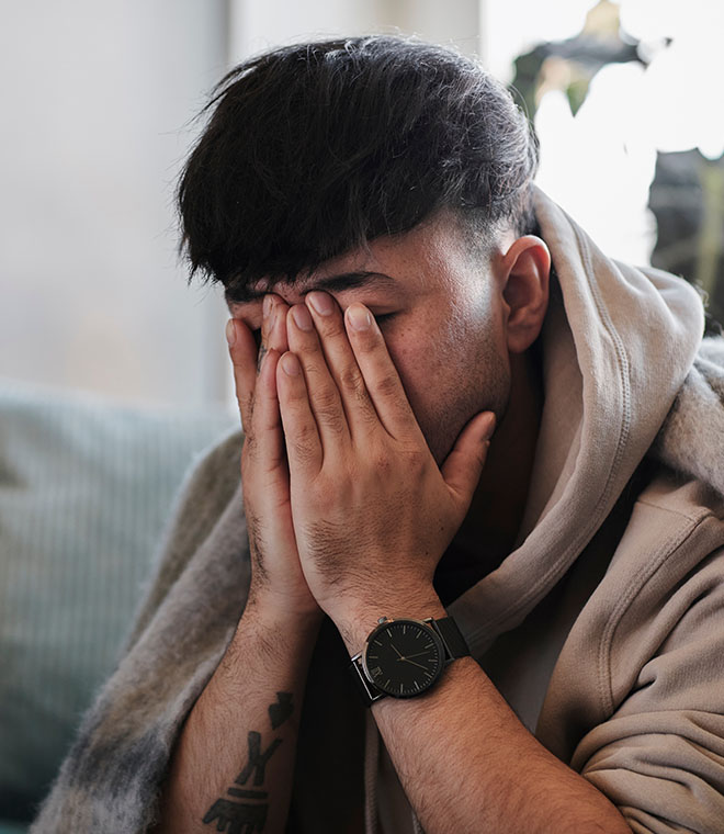 Man wrapped in blanket with hands over face