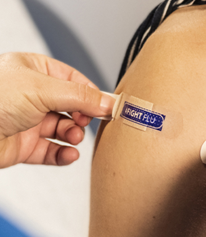 Placing a fight the flu band-aid on woman's arm