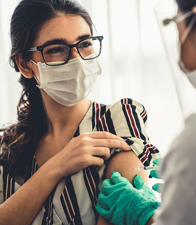 Young white woman in mask getting a shot in her arm