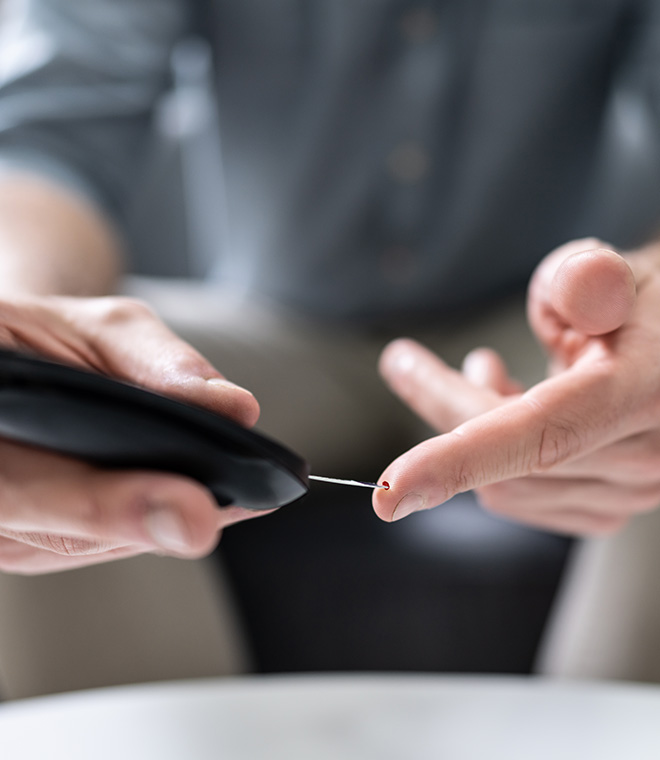 Person pricking finger to monitor blood sugar