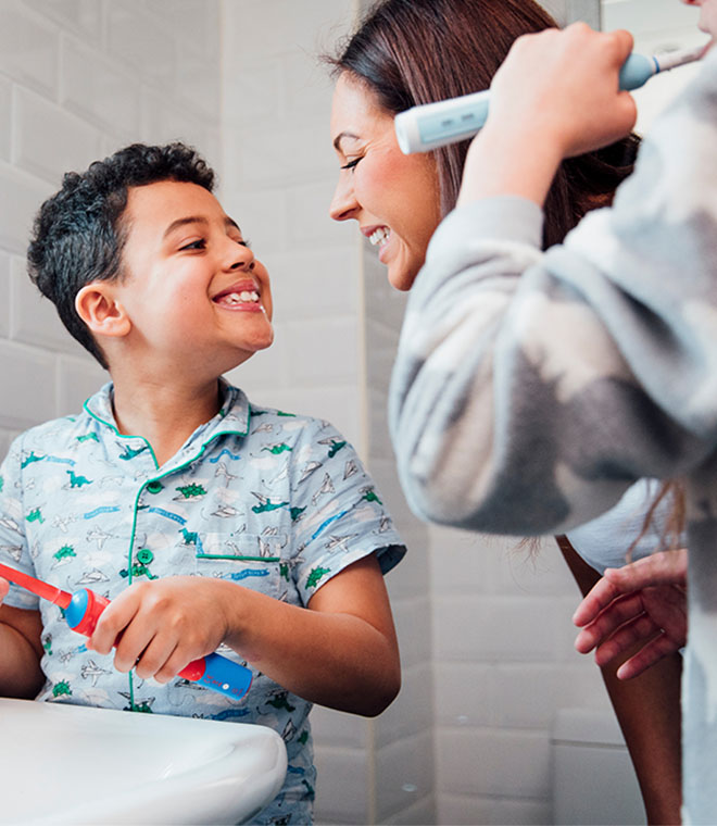 Mom helping two children brush their teeth