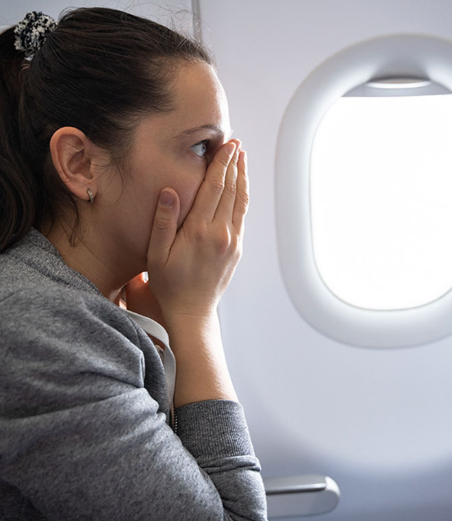 Woman in airplane covering her face