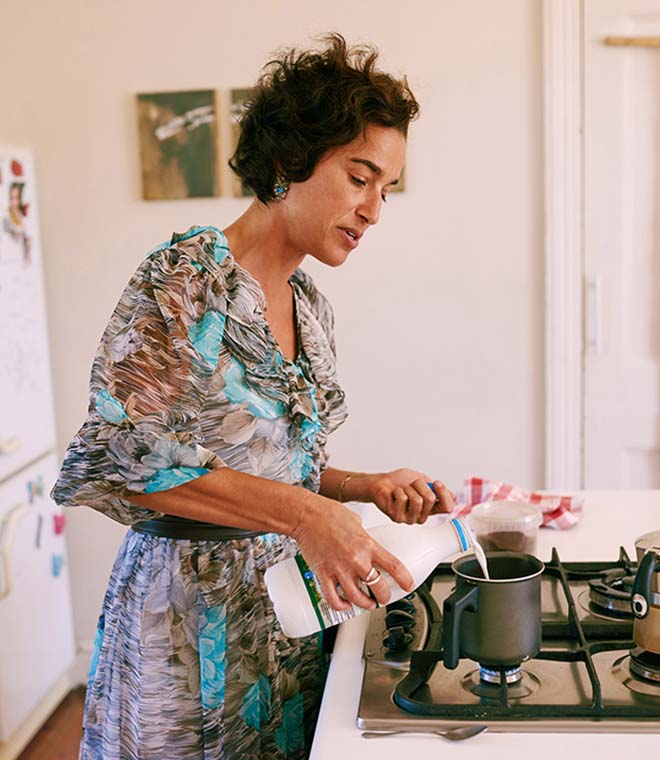 Woman in her 50s adding milk to coffee