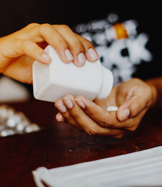 Hands retrieving a white pill out of a bottle