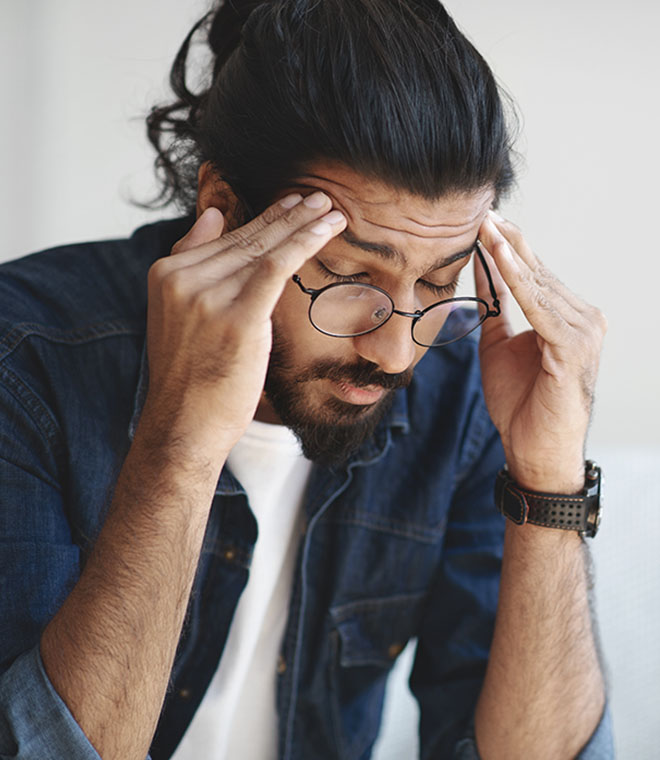 Bearded man holding his temples in pain