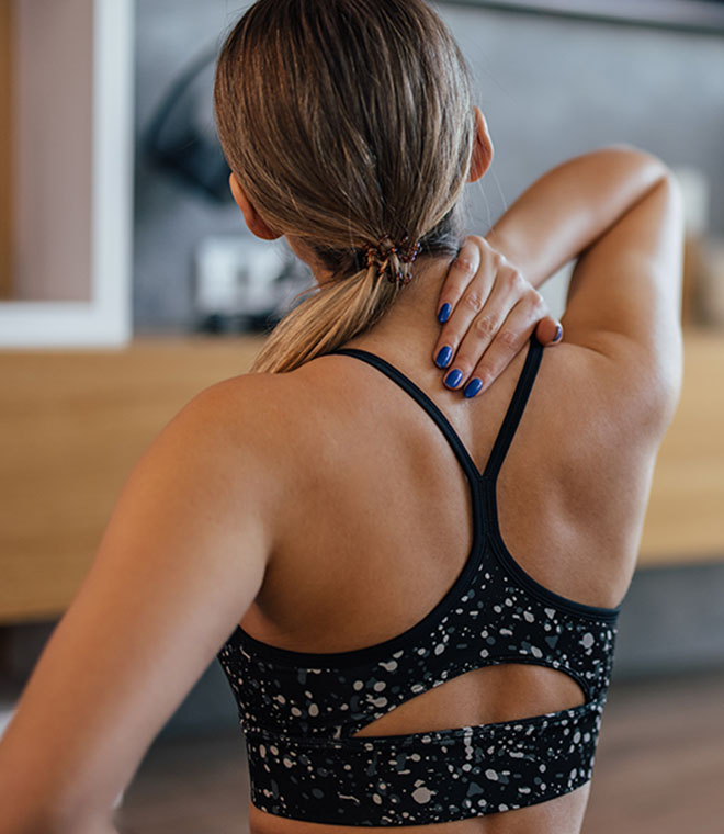 Young blonde woman holding her upper back and neck