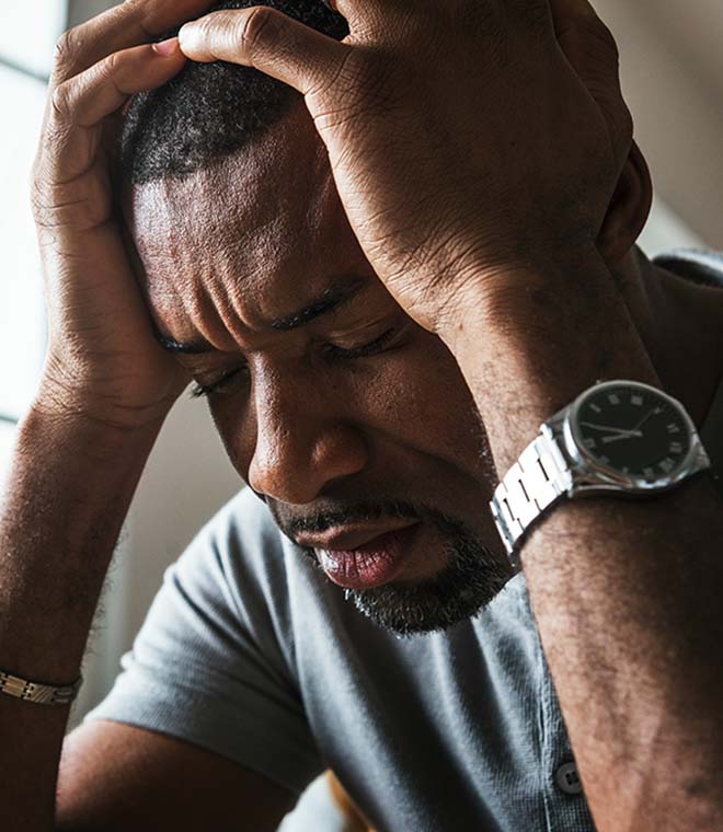 Black man holding his head in pain