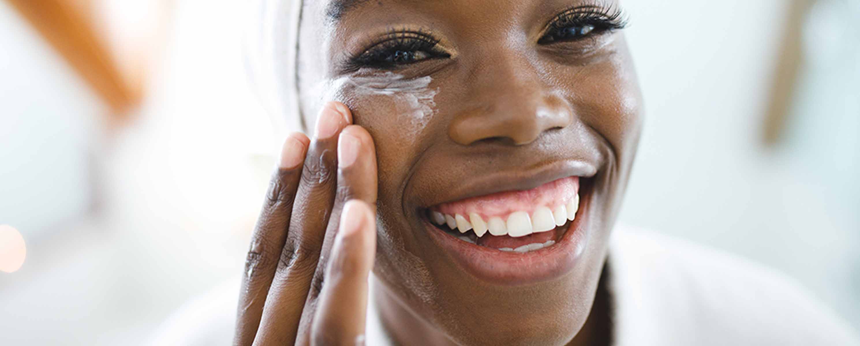 Young black woman applying moisturizer