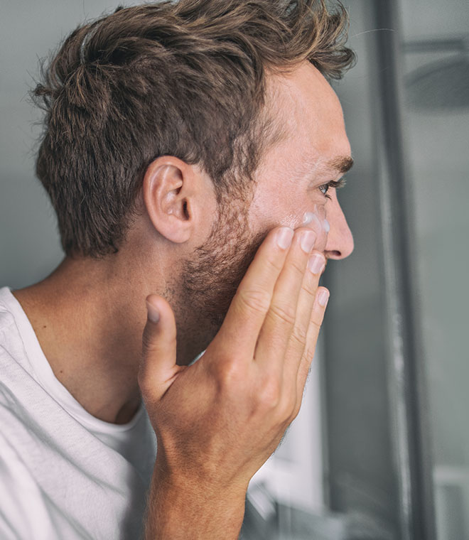 Millennial man applying moisturizer