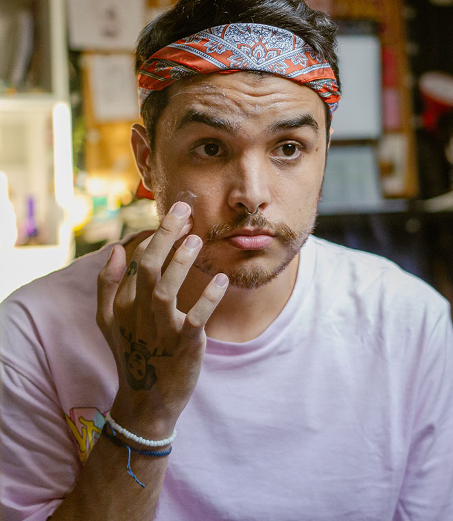 Millennial man applying acne medication to his cheek