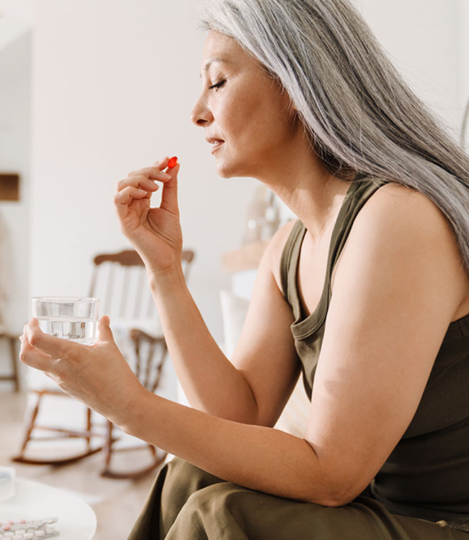 Woman with long gray hair taking medicine