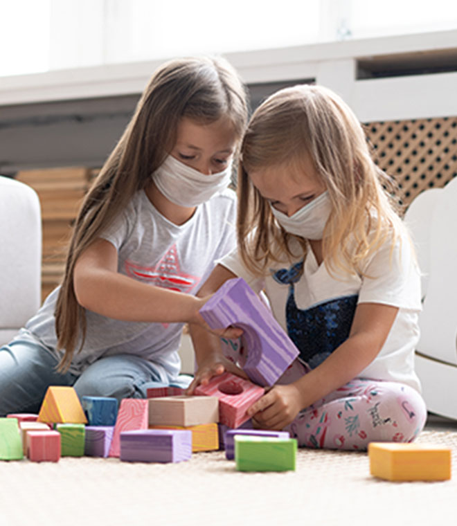 Girls with masks playing with blocks