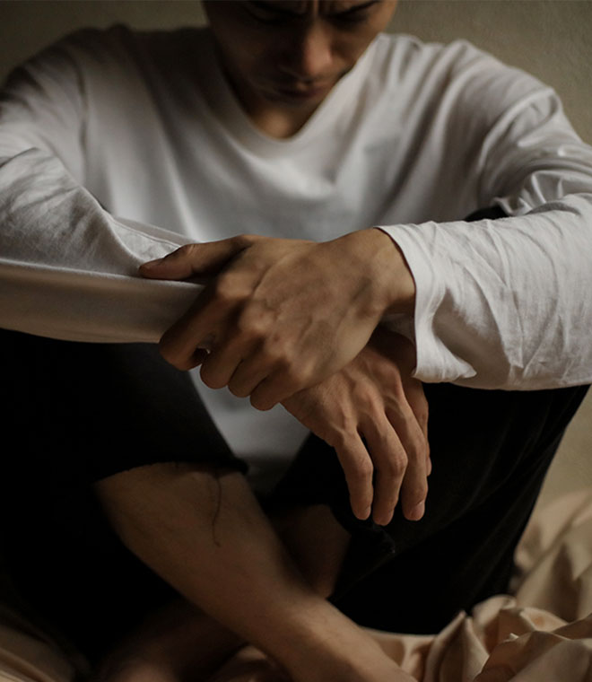 Young man in a white shirt sitting hunched over