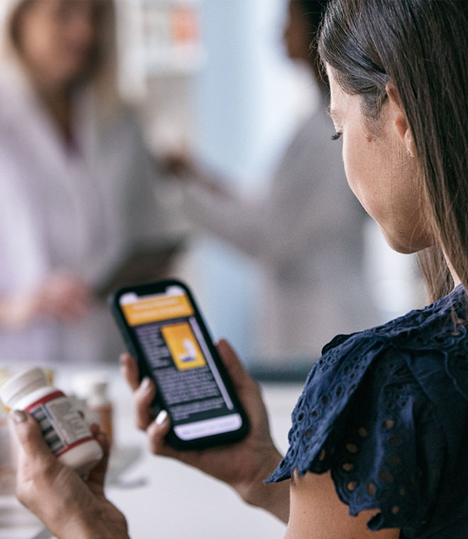 Young woman checking vitamin bottle information on phone