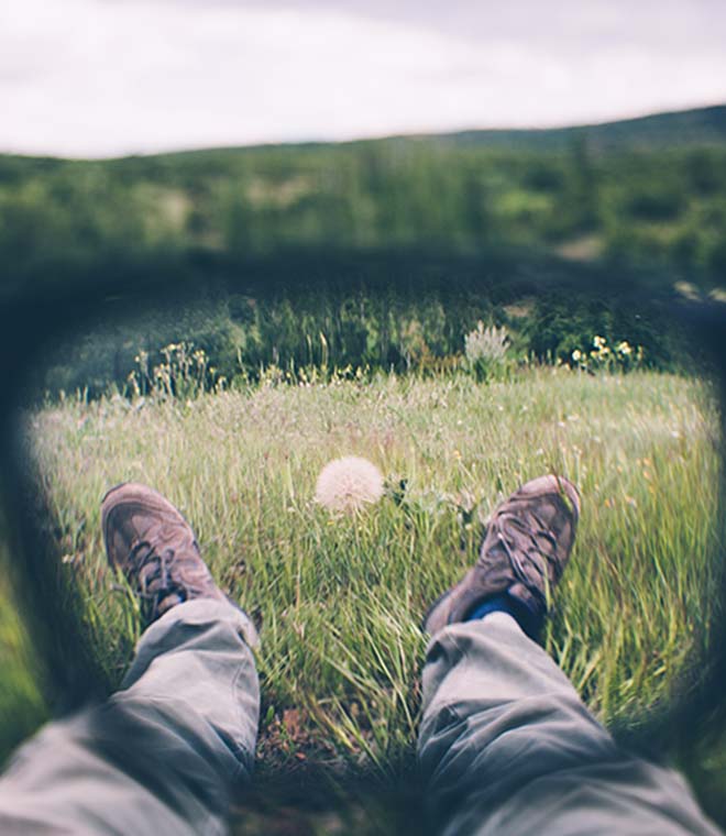 Man laying in a field through lens of glasses