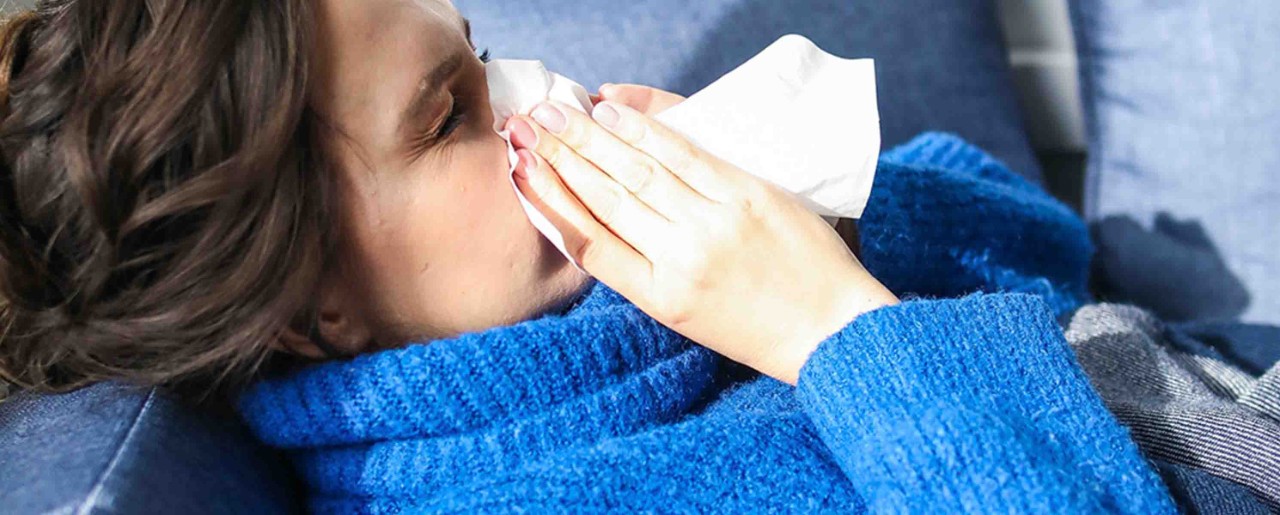 Woman in a blue robe blowing her nose