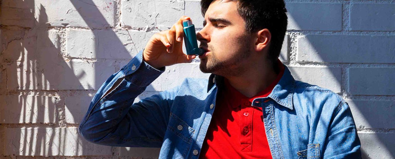 Man in a red shirt using an inhaler