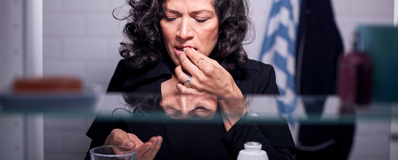 Woman in her 50s touching her lips in bathroom