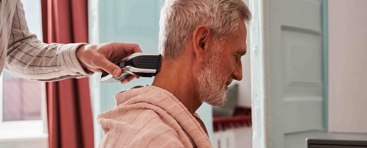 Caregiver cutting older man's hair